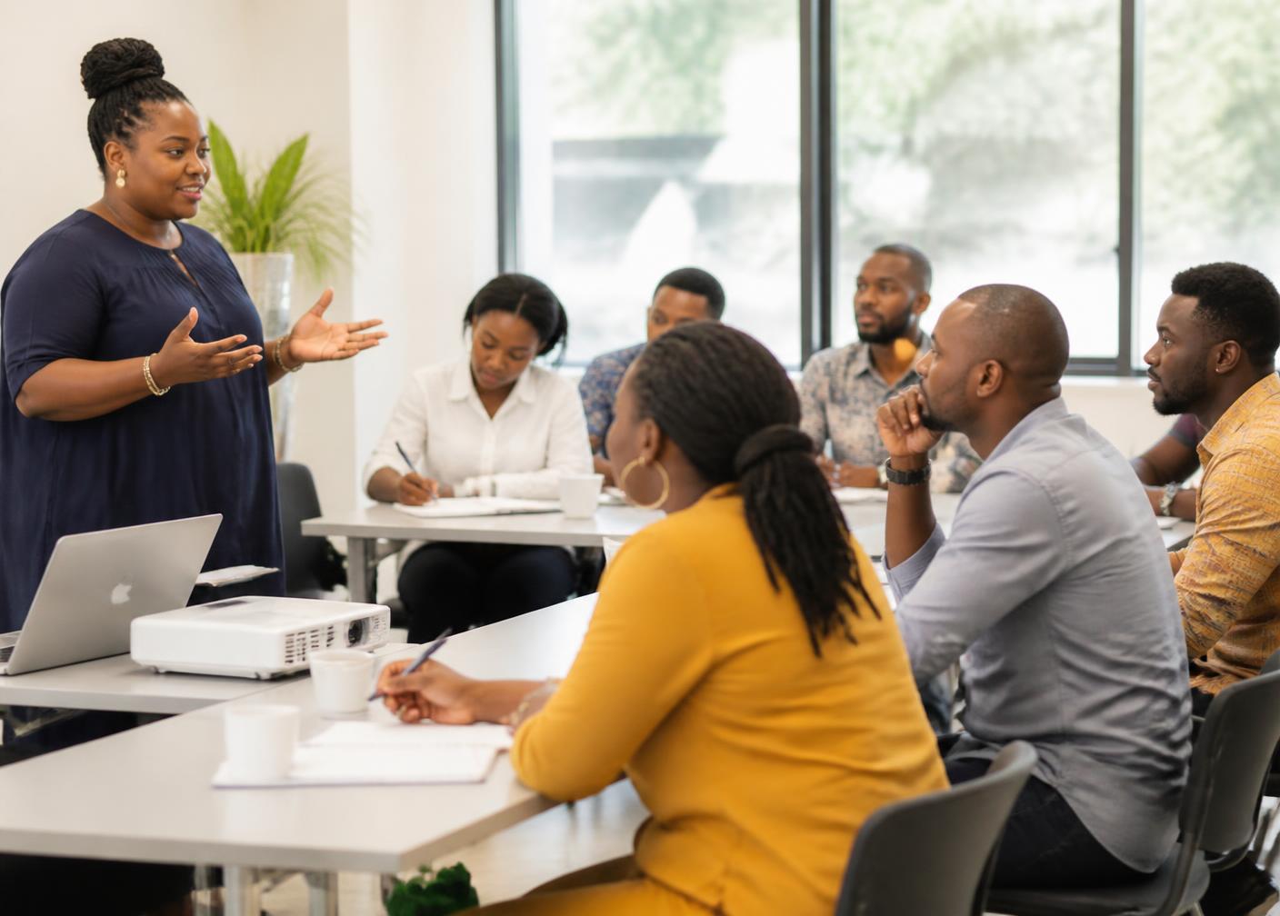 A practitioner leading a masterclass for a small group of African entrepreneurs in a training room.